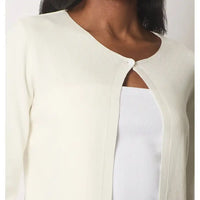 Close-up of a person wearing a white long-cardigan top with cut-out shoulders on a plain background.