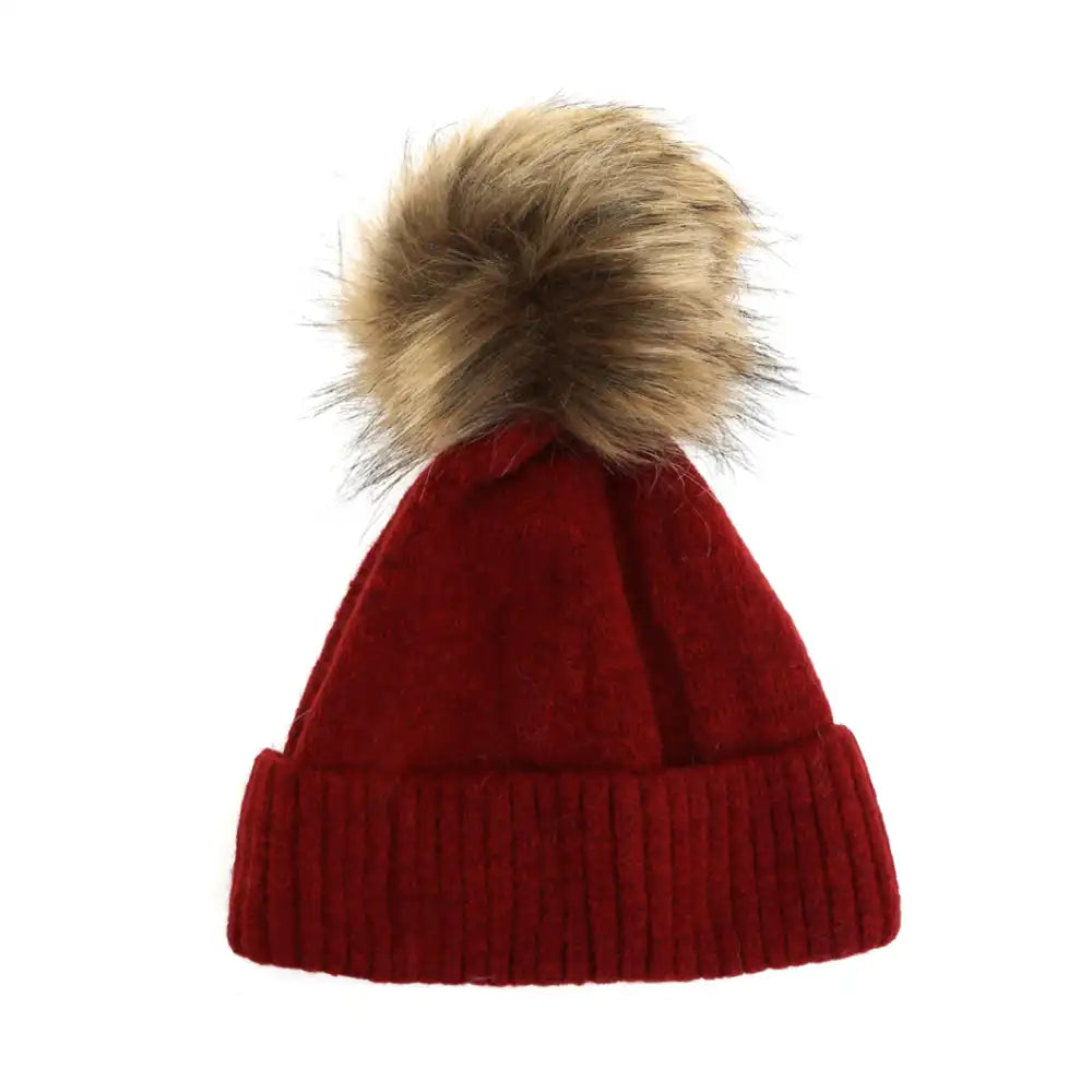 Red knit beanie with a large fur pom-pom on a white background
