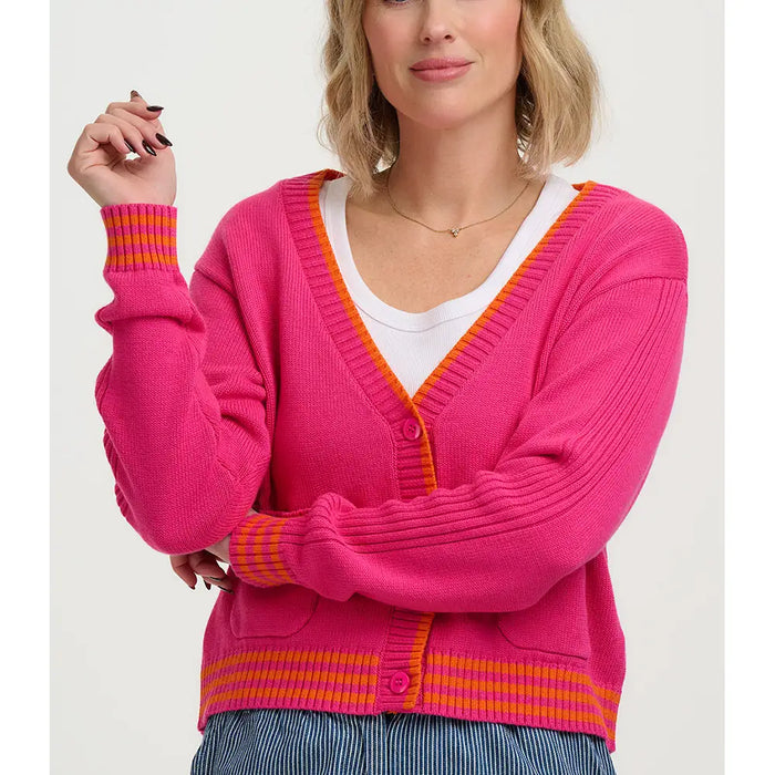 Woman wearing a bright pink cardigan with orange accents on a white background