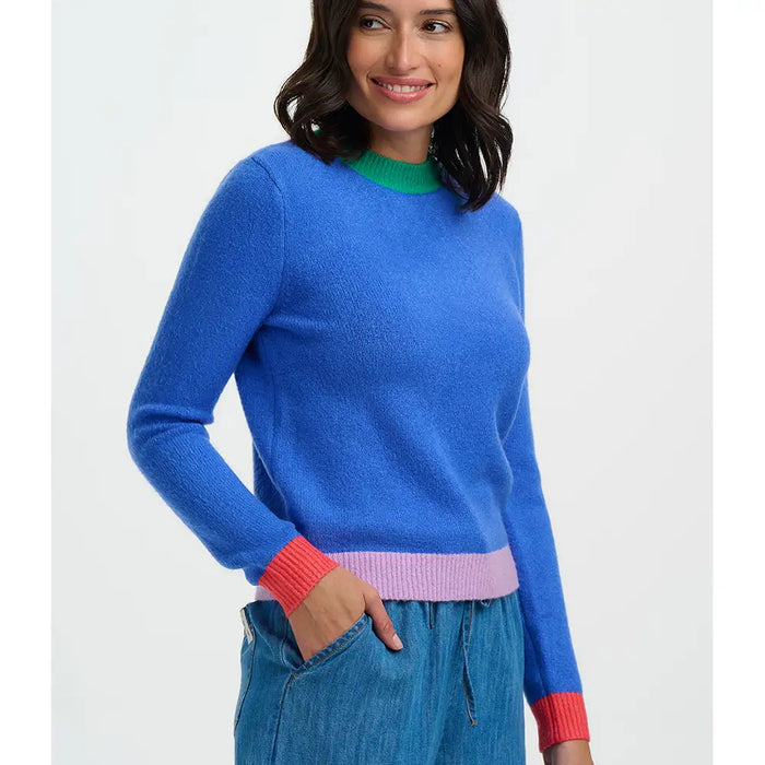Woman wearing a blue sweater with colorful cuffs and hem on a white background
