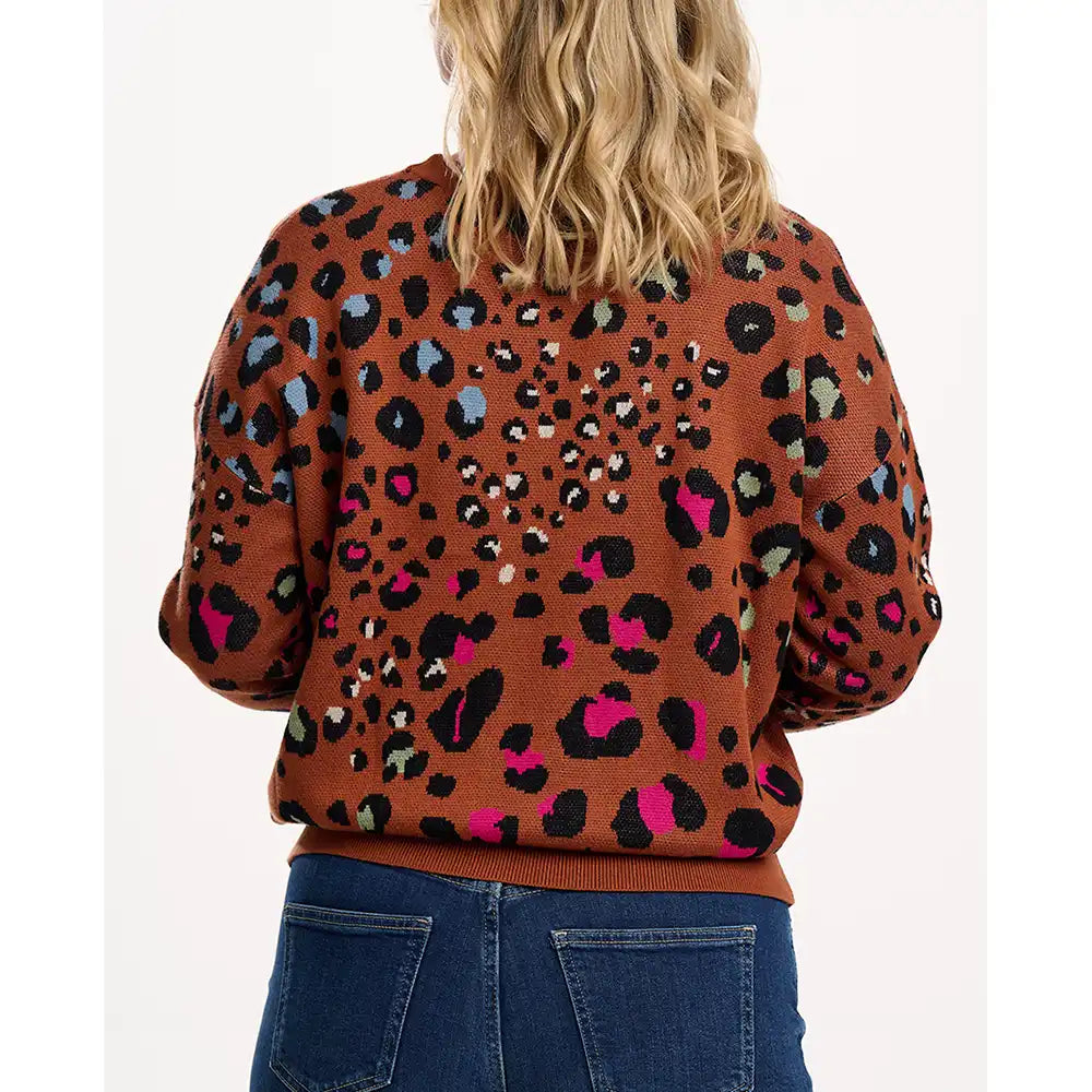 Person wearing a brown sweater with colorful leopard print pattern on a white background