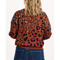 Person wearing a brown sweater with colorful leopard print pattern on a white background