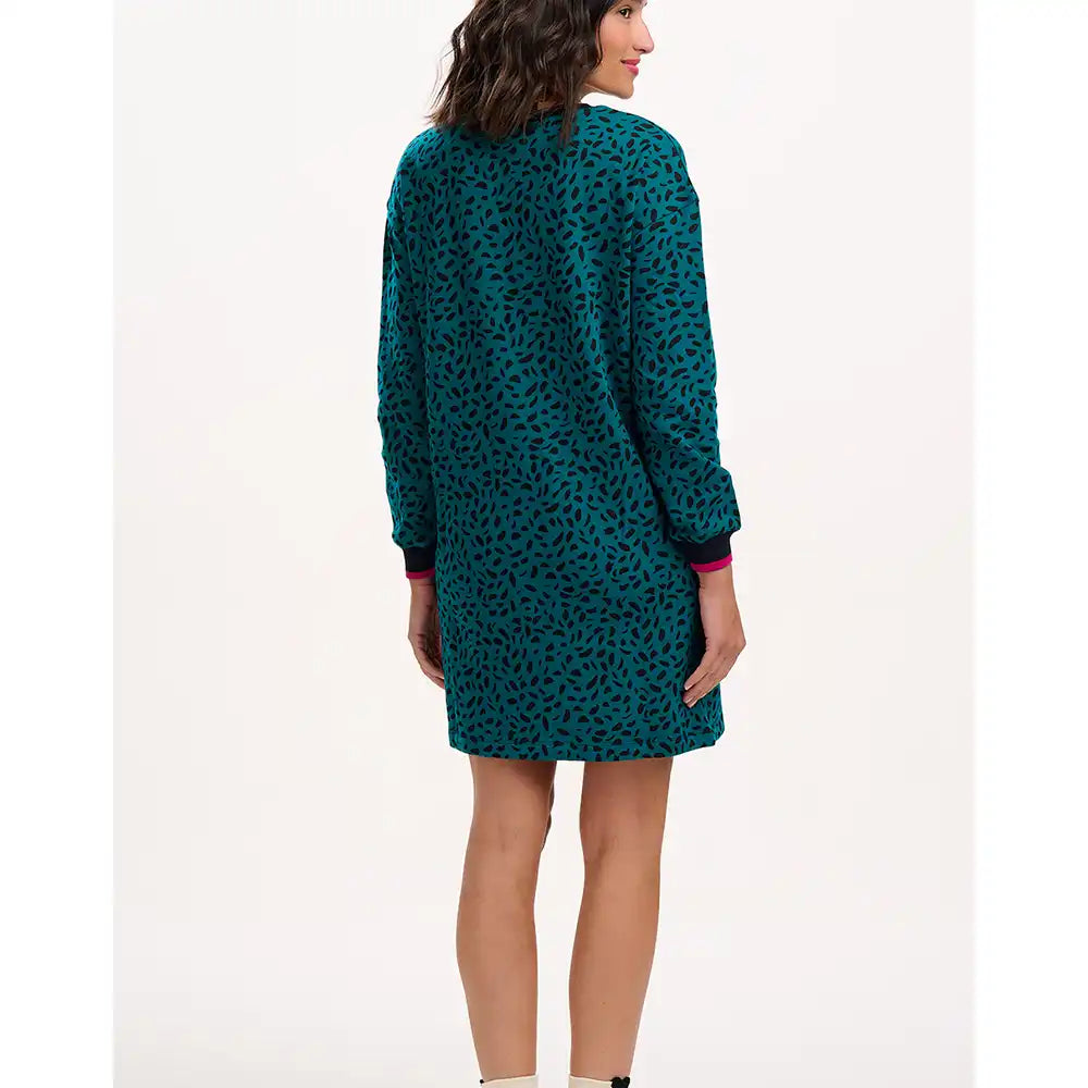 Woman wearing a teal patterned dress on a white background