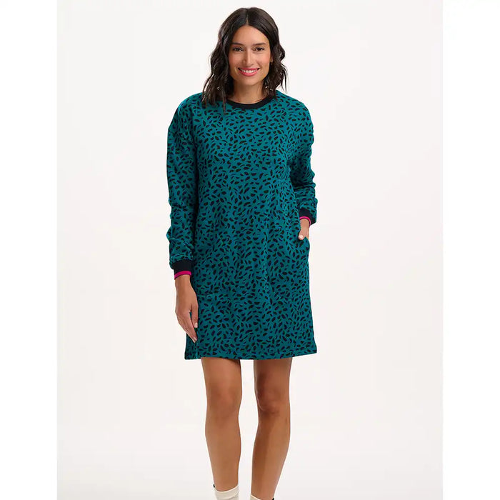 Woman wearing a teal patterned dress on a white background