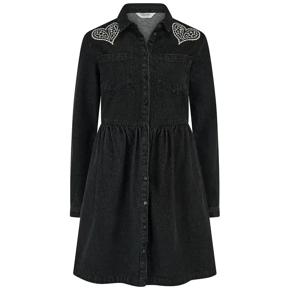 A woman wearing a black denim-style long-sleeve shirt dress with heart-shaped silver embellishments on the shoulders, shown against a plain white background.
