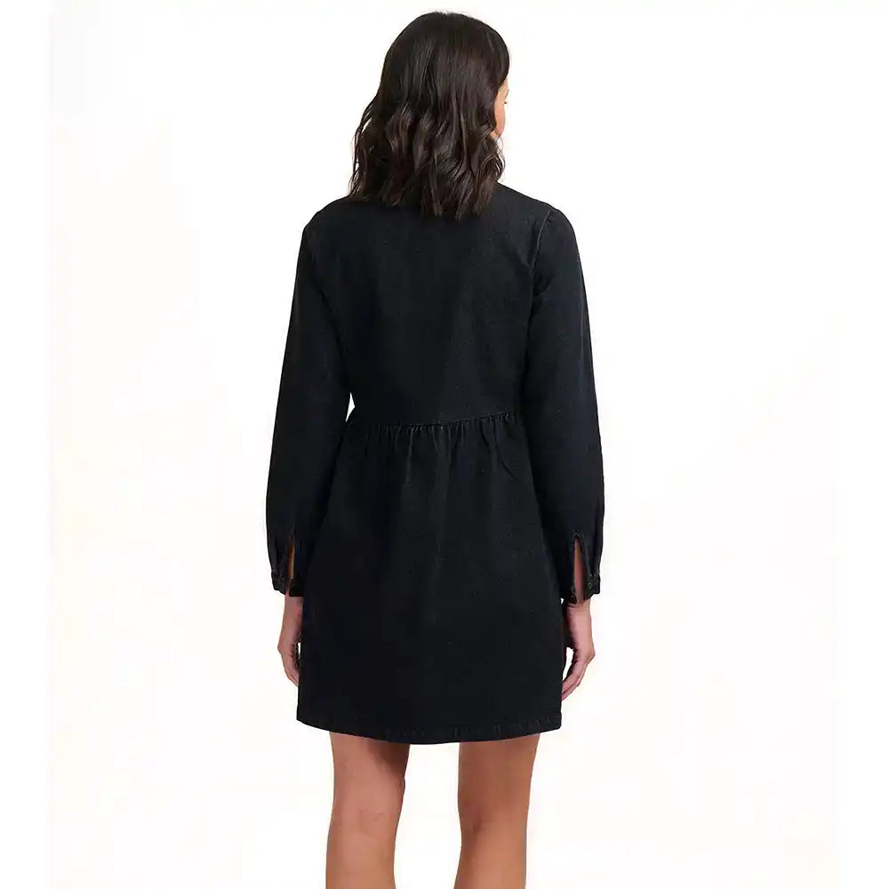 A woman viewed from the back wearing a black long-sleeve mini dress with a gathered waist and side slits, photographed against a plain white studio background.