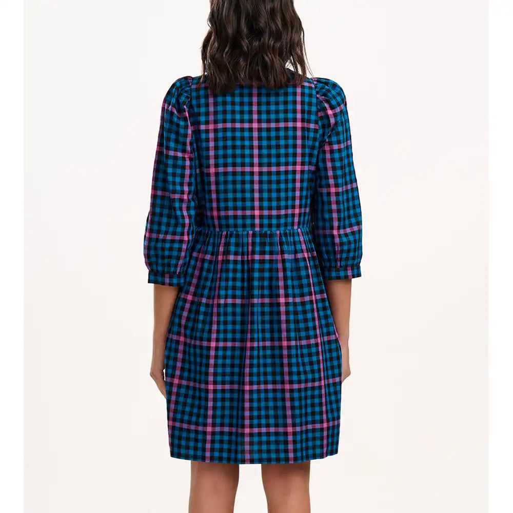 Back view of a person wearing a blue and pink plaid dress on a white background