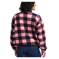A person shown from the back wearing a fuzzy long-sleeve fleece jacket with a large pink, brown, and navy blue check pattern, paired with blue jeans, against a white studio background.