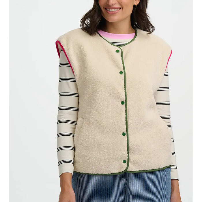 Woman wearing a cream-colored vest with green buttons on a white background