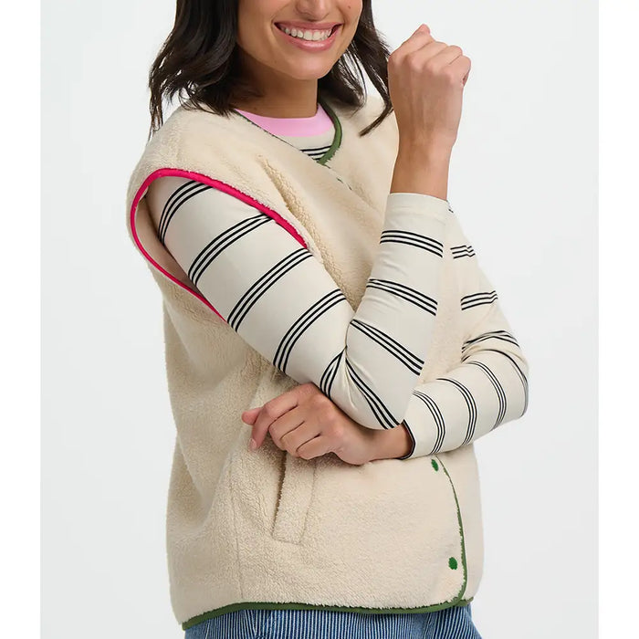 Woman wearing a cream-colored fleece vest with striped sleeves on a white background