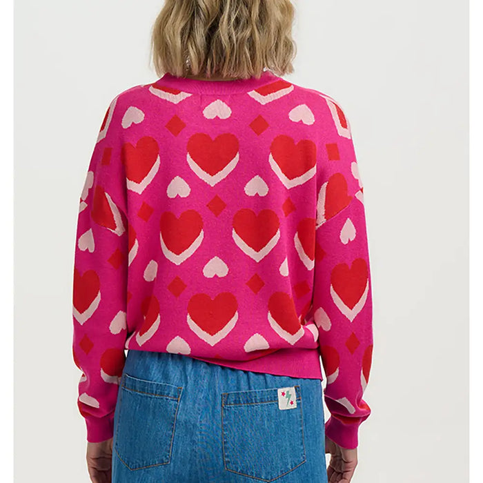 Person wearing a pink sweater with red heart patterns on a white background