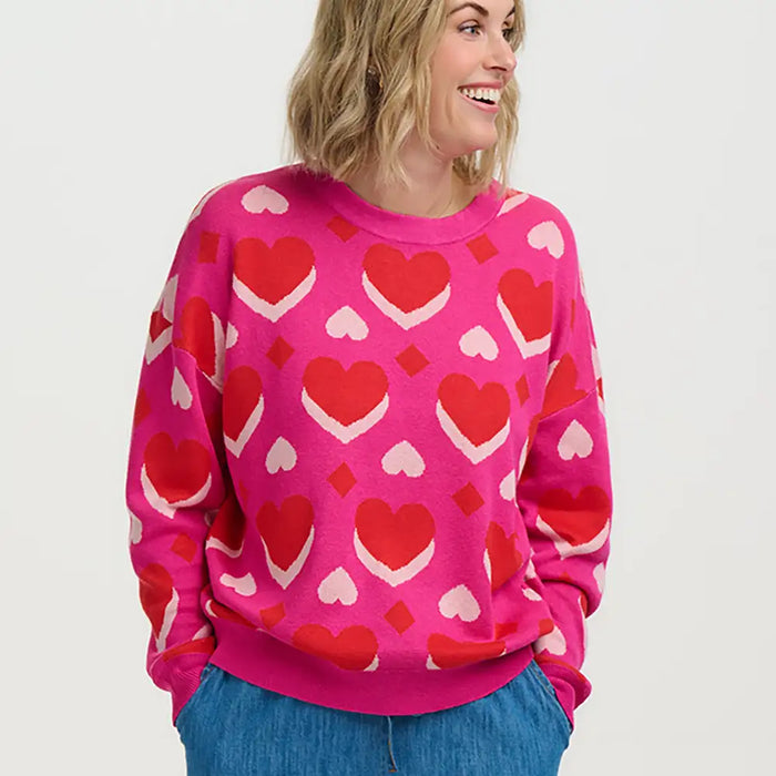 Person wearing a pink sweater with red heart patterns on a white background