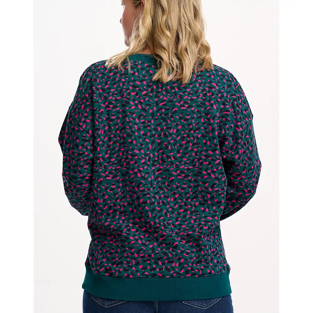 Person wearing a dark green sweatshirt with pink pattern on a white background