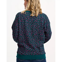 Person wearing a dark green sweatshirt with pink pattern on a white background