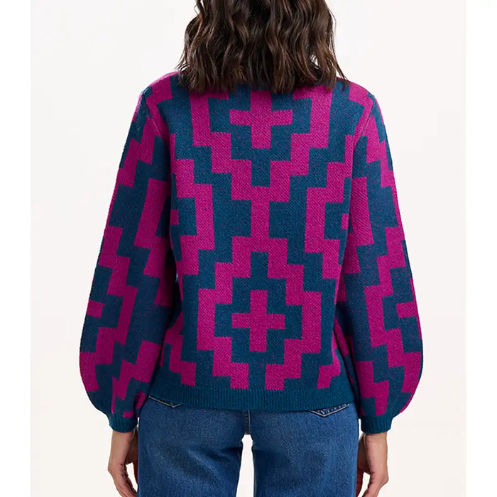 Person wearing a blue and pink geometric patterned sweater on a white background