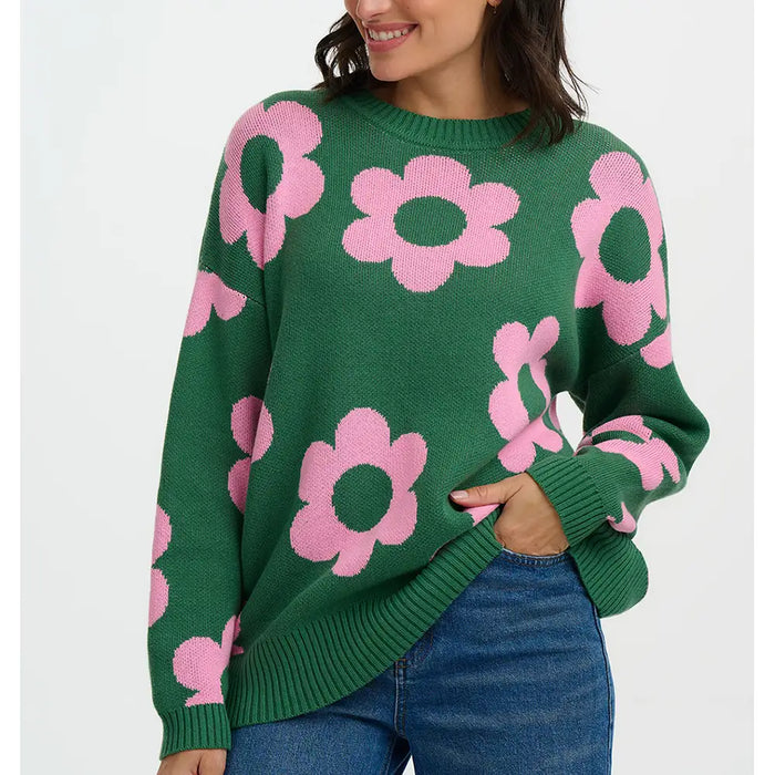 Green sweater with pink floral patterns worn by a person on a white background