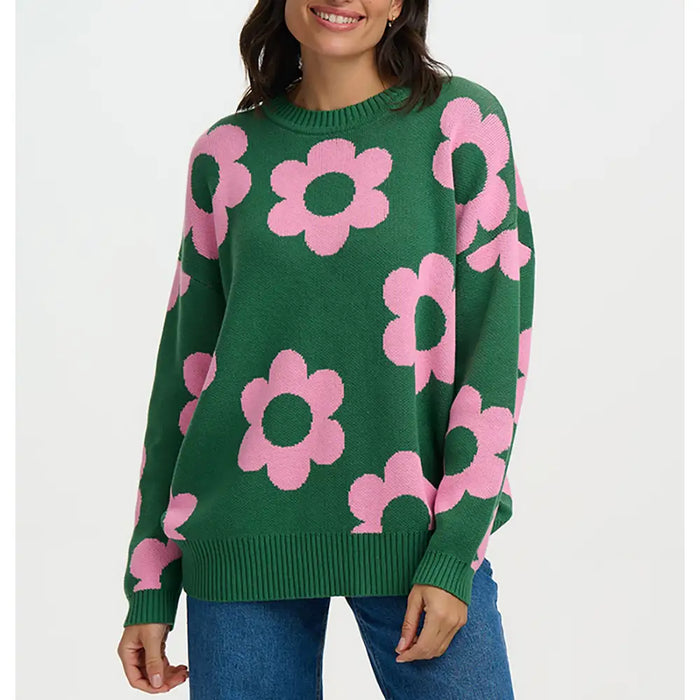 Green sweater with pink floral patterns worn by a person on a white background