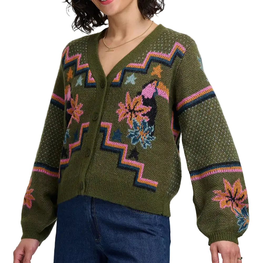 Woman wearing khaki green four button cardigan with flowers and toucans pattern. She is in a white studio environment.