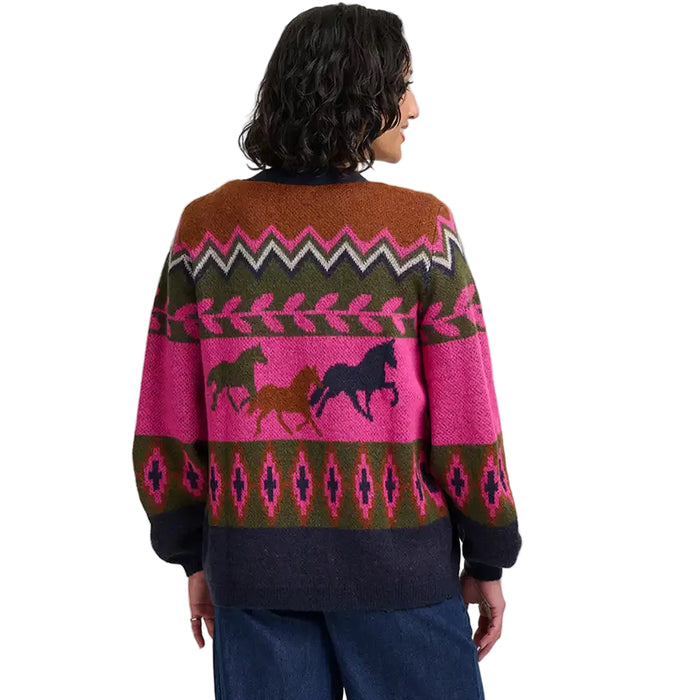 Woman wearing a multi coloured cardign with a running horses motif. She is facing away from the camera. She is in a white studio environment.
