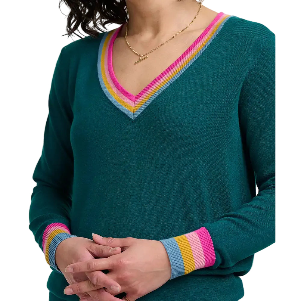 A woman wearing a teal green V-neck sweater with pink, yellow, and light blue striped trim along the neckline.