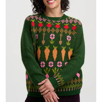 A woman wearing a dark green knit sweater with a colorful carrot and flower pattern, shown from the waist up against a light gray background.