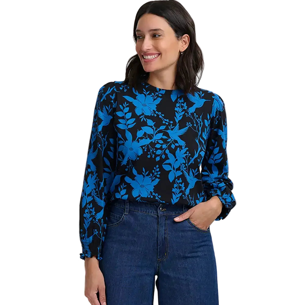 Woman wearing a round neck top with a blue pattern of hummingbirds and flowers on a black background.