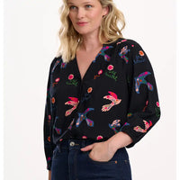 Woman wearing a black blouse with colorful bird patterns on a white background
