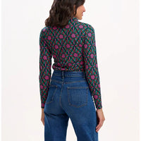 Woman wearing a patterned shirt and jeans on a white background