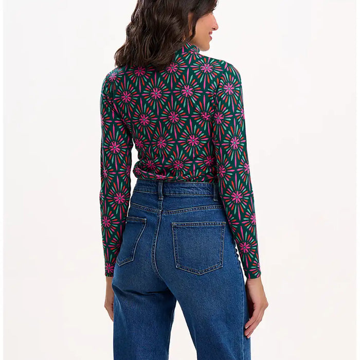 Woman wearing a patterned shirt and jeans on a white background