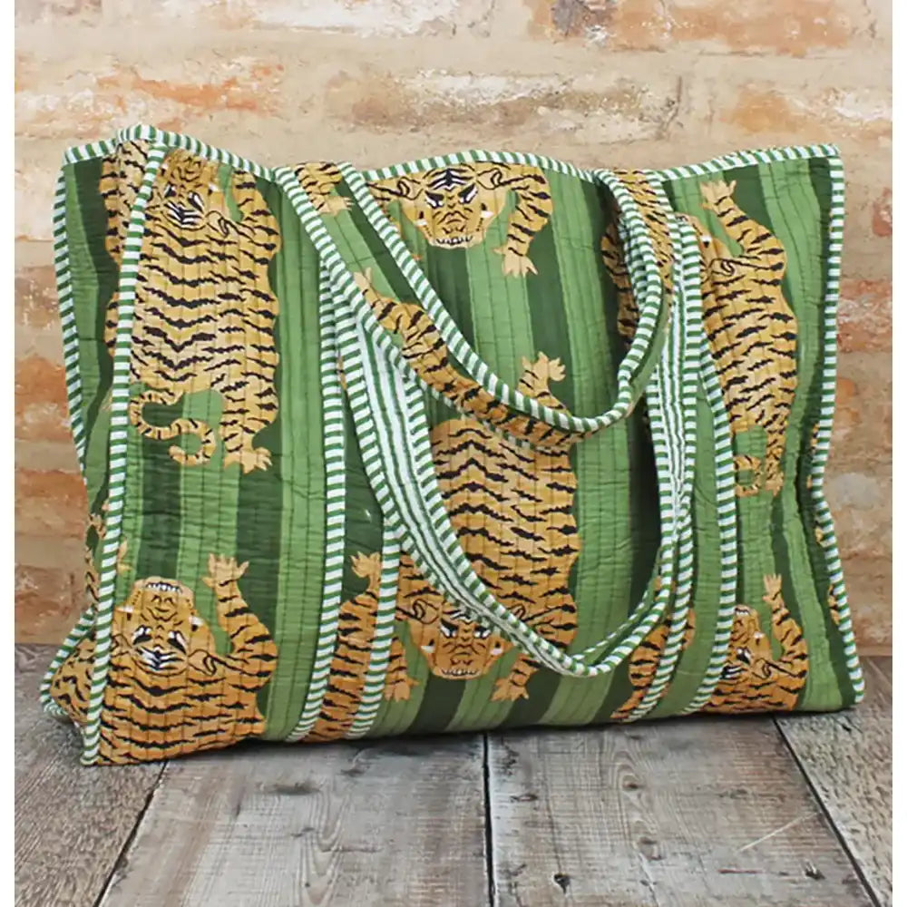 Green tote bag with tiger pattern on a wooden surface and brick wall background