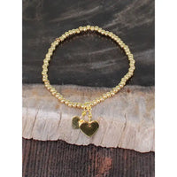 Gold beaded bracelet with heart charms on a wooden surface