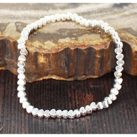 Silver beaded bracelet on a textured wooden surface