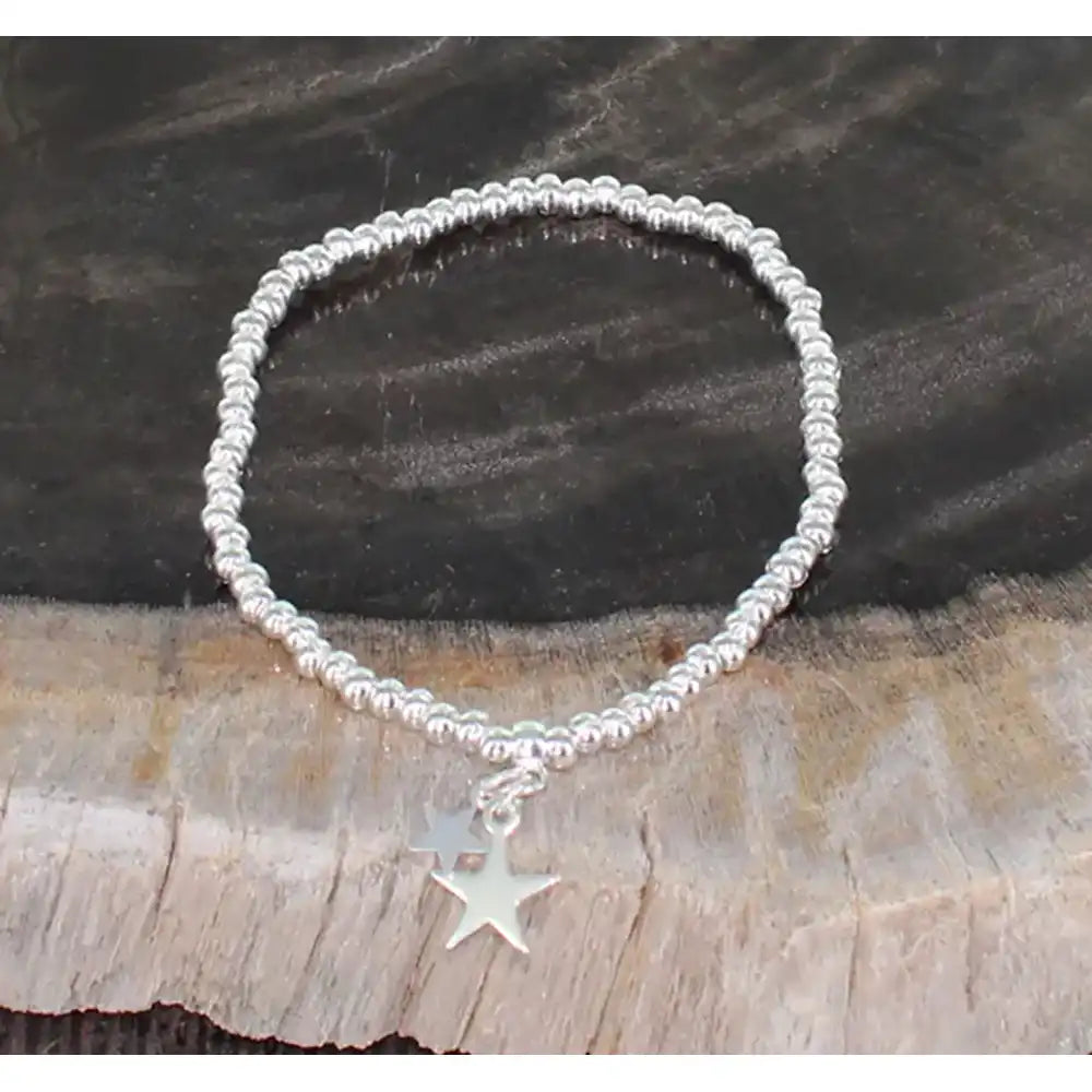 Silver bracelet with a star charm on a wooden surface
