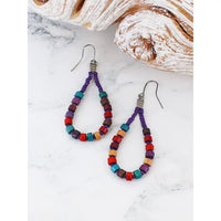 Colorful beaded earrings on a marble surface with seashells in the background