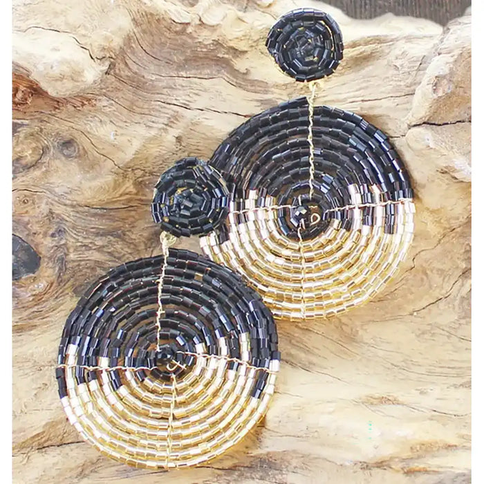 Black and gold beaded earrings on a wooden surface