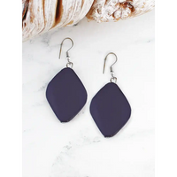 Navy blue earrings on a white surface with seashells in the background