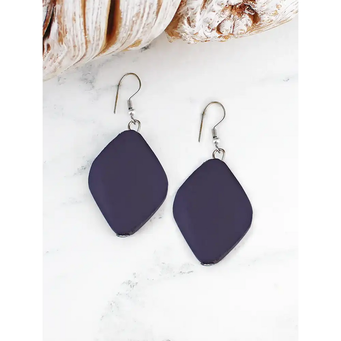 Navy blue earrings on a white surface with seashells in the background
