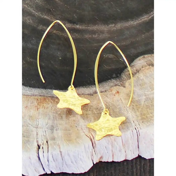 Gold star earrings on a natural stone background