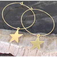Gold hoop earrings with star pendants on a wooden surface