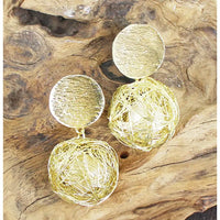 Gold sphere earrings on a wooden surface