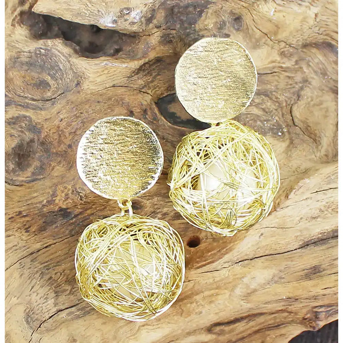 Gold sphere earrings on a wooden surface