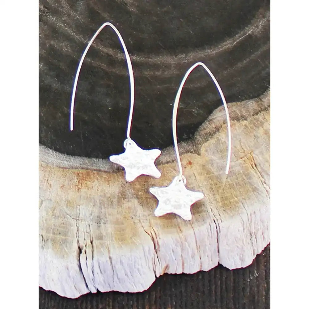 Star-shaped silver earrings on a wooden surface