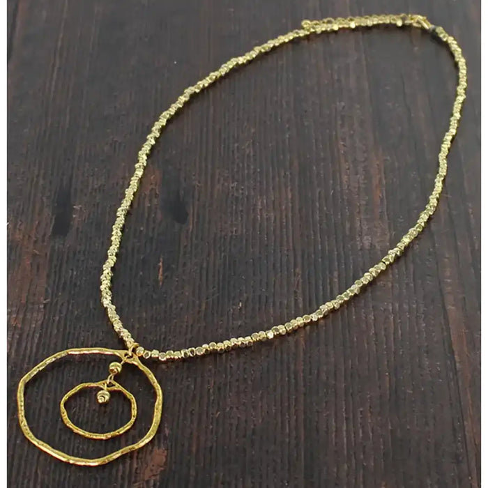 Gold necklace with a circular pendant on a dark wooden surface