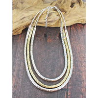 Necklace with three strands of gold and silver on a wooden surface