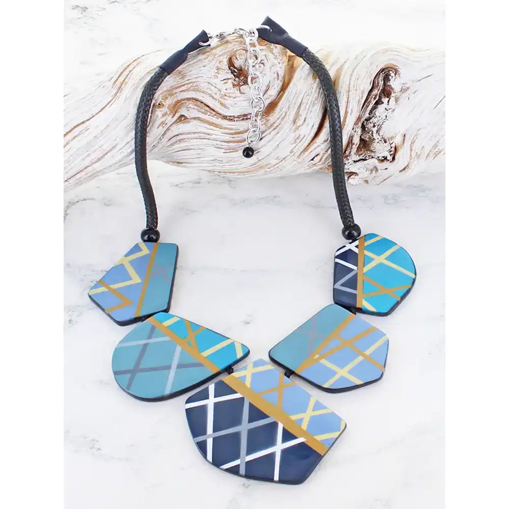 Necklace with geometrically patterned pendants on a textured surface