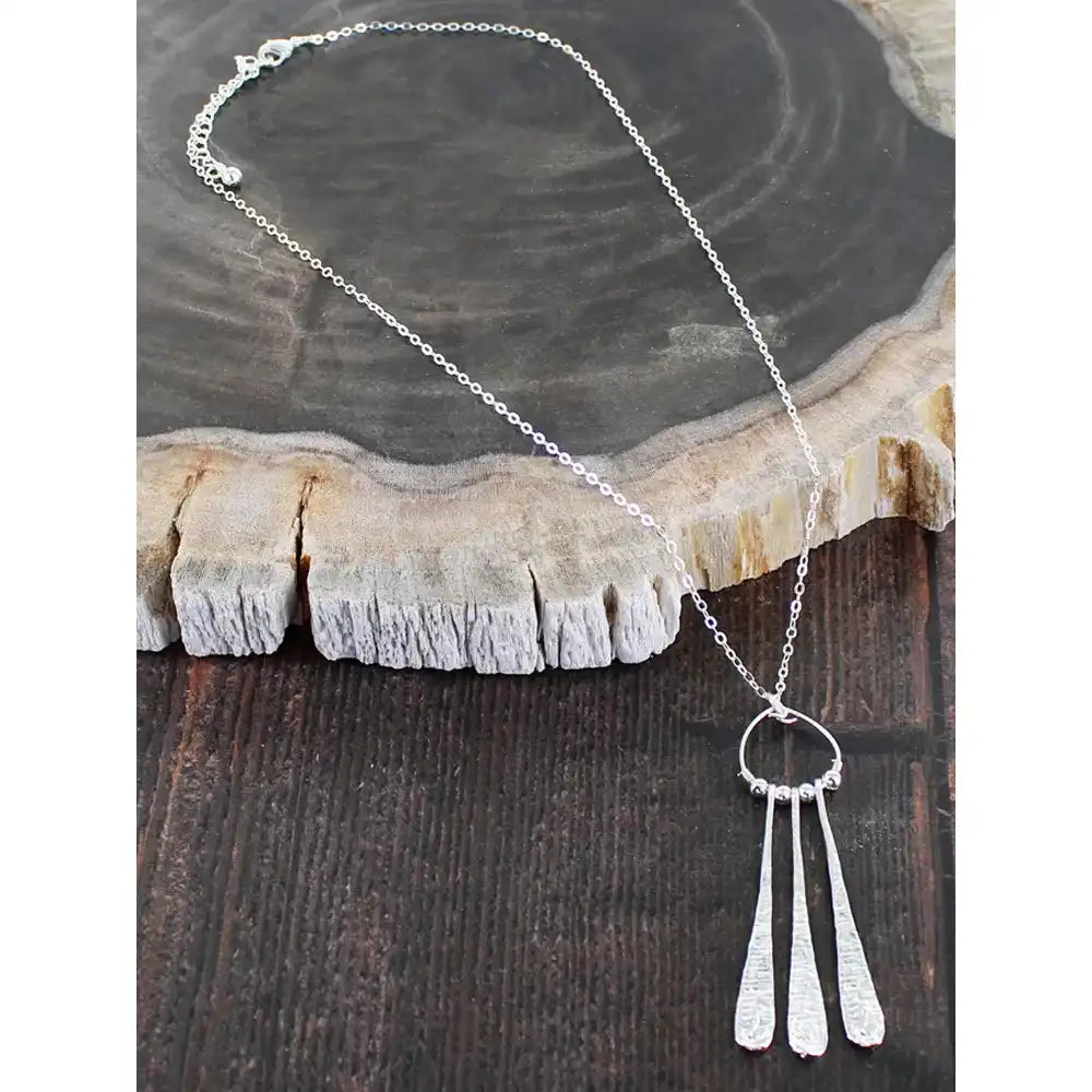 Silver necklace with a pendant on a wooden surface