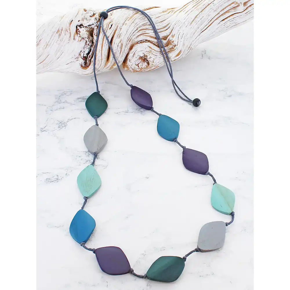 Necklace with colorful beads on a white surface with driftwood