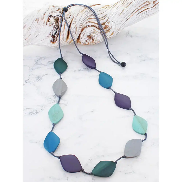 Necklace with colorful beads on a white surface with driftwood