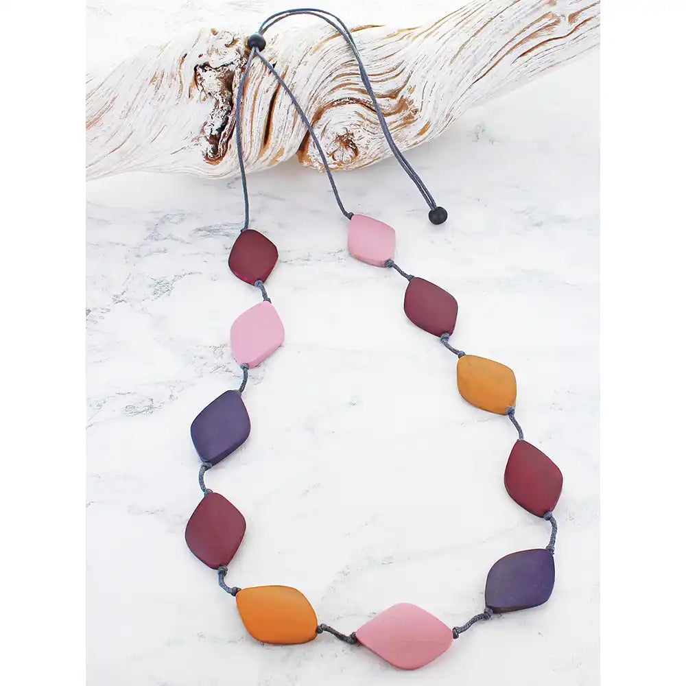 Necklace with colorful leaf-shaped beads on a white marble surface