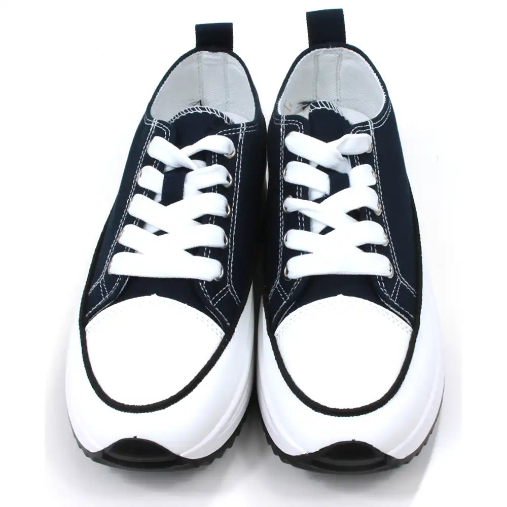 Lace up platform trainers in navy blue. White trim around the base above the black soles. White toe caps. Fabric shoe bodies. Navy blue pull on tabs at the ankles. White stitching detail. Front view.
